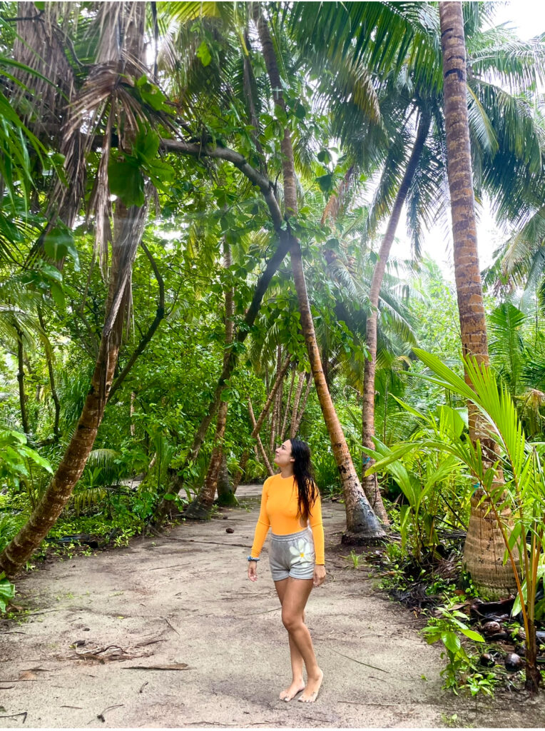 Mujer caminando descalza por un sendero rodeado de palmeras y vegetación tropical
