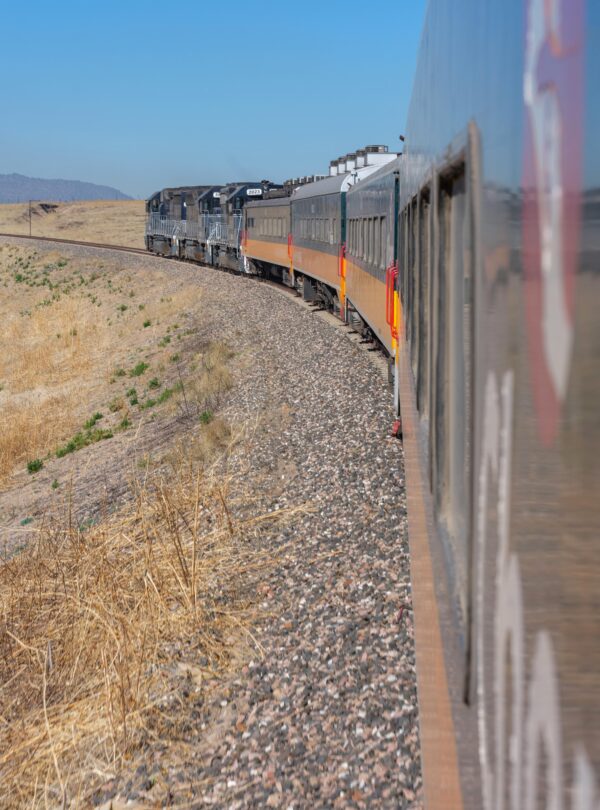 Tren viajando por un paisaje árido y despejado, capturado desde una ventana del vagón.