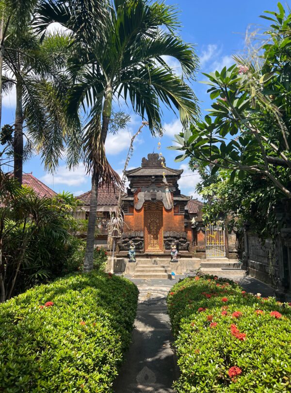 Entrada tallada de un templo hindú tradicional en Bali, con esculturas ornamentadas y una estatua azul visible en el interior.