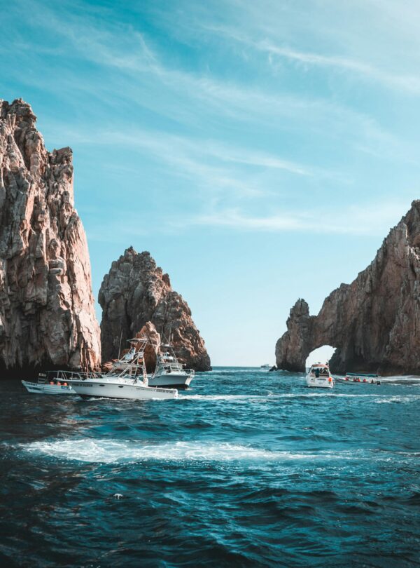 Formaciones rocosas y embarcaciones turísticas en el Arco de Cabo San Lucas, México, en un día soleado.