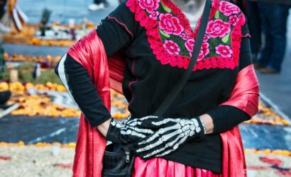 Mujer disfrazada de Catrina con maquillaje tradicional y vestimenta colorida durante celebración del Día de Muertos en México.