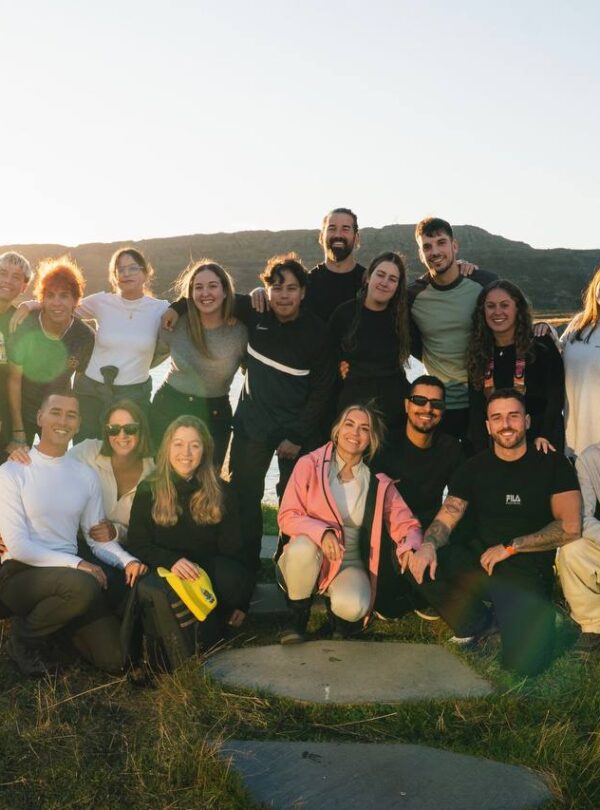 Grupo de personas posando al atardecer junto a un lago rodeado de colinas.