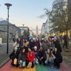 Grupo de personas posando en una calle con los colores del arcoíris, con la iglesia Hallgrímskirkja al fondo en Reikiavik, Islandia.