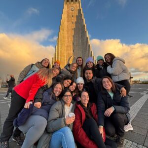 Grupo de personas sonriendo frente a la iglesia Hallgrímskirkja en Reikiavik al atardecer.