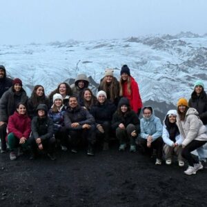 Grupo de personas posando frente a un extenso glaciar cubierto de hielo y ceniza volcánica en Islandia.