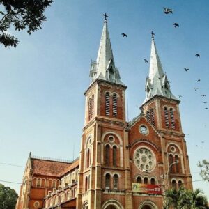 Fachada de la Catedral de Notre-Dame de Saigón en Ciudad Ho Chi Minh, Vietnam, con sus dos torres gemelas y arquitectura de ladrillo rojo.